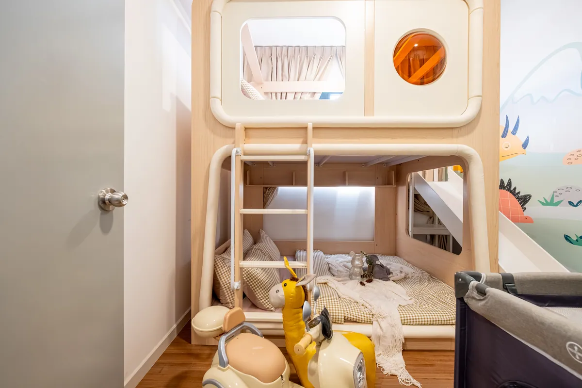 The bunk house with a round window, ride-on toys and a baby cot